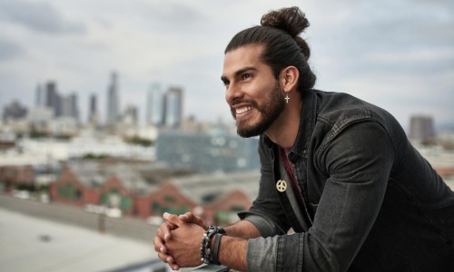 a man leaning on a railing with a city in the background