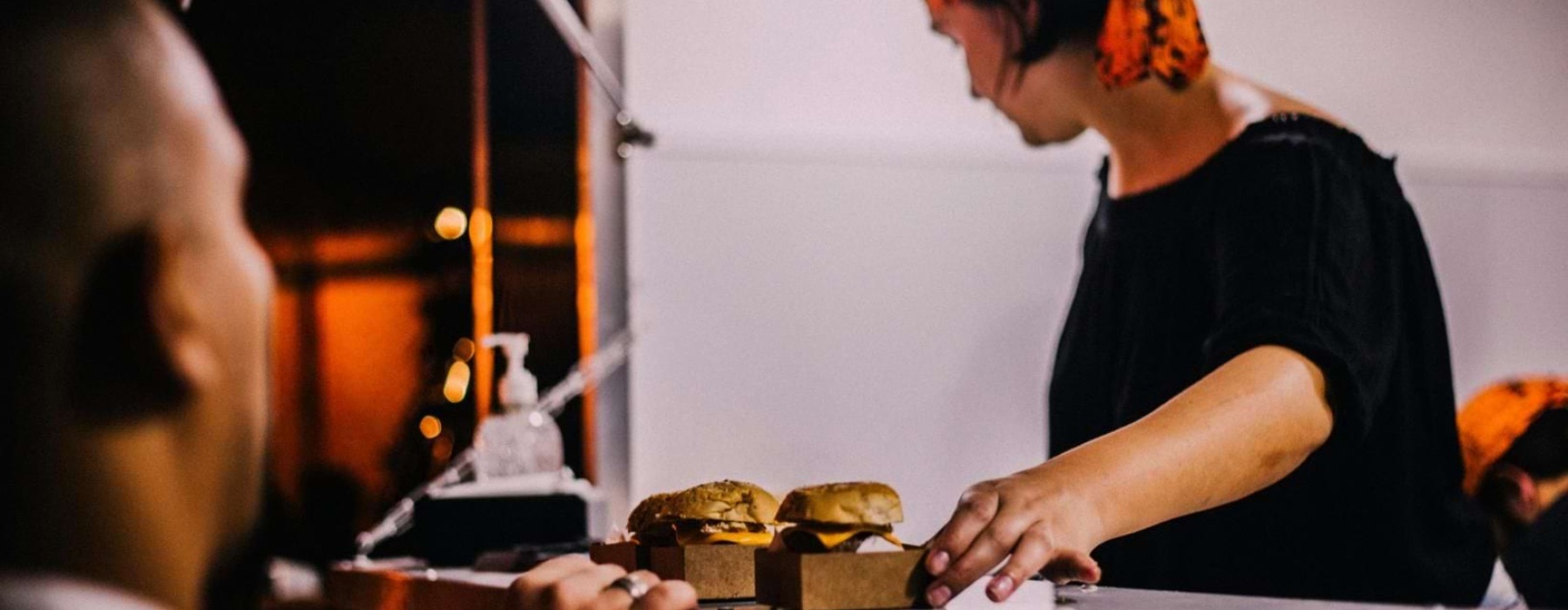 a man serving burgers to a customer over the counter