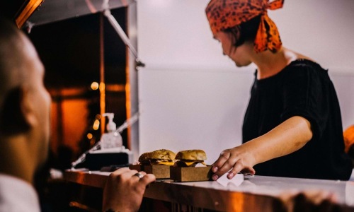 a man serving burgers to a customer over the counter